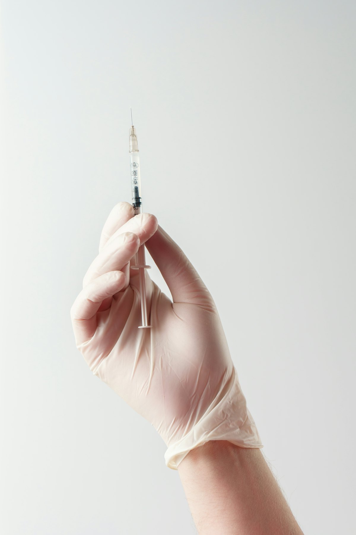 Gloved hand holding a fine needle used for acne scar subcision